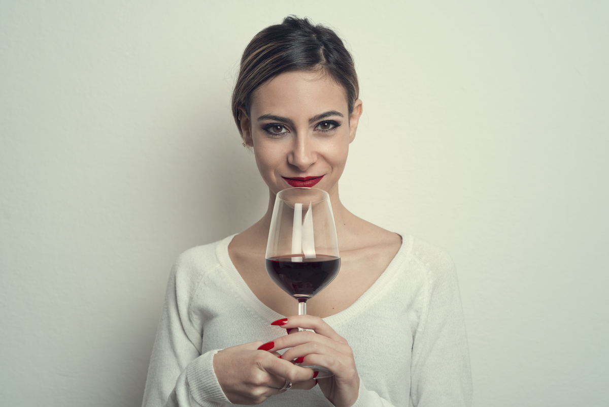 nő fehér felsőben, kezében vörösbor pohárban