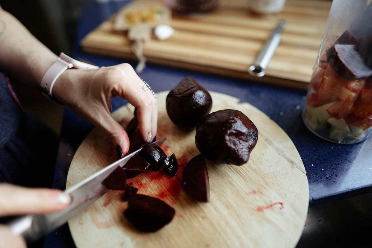 női kéz főtt céklát aprít kerek vágódeszkán
