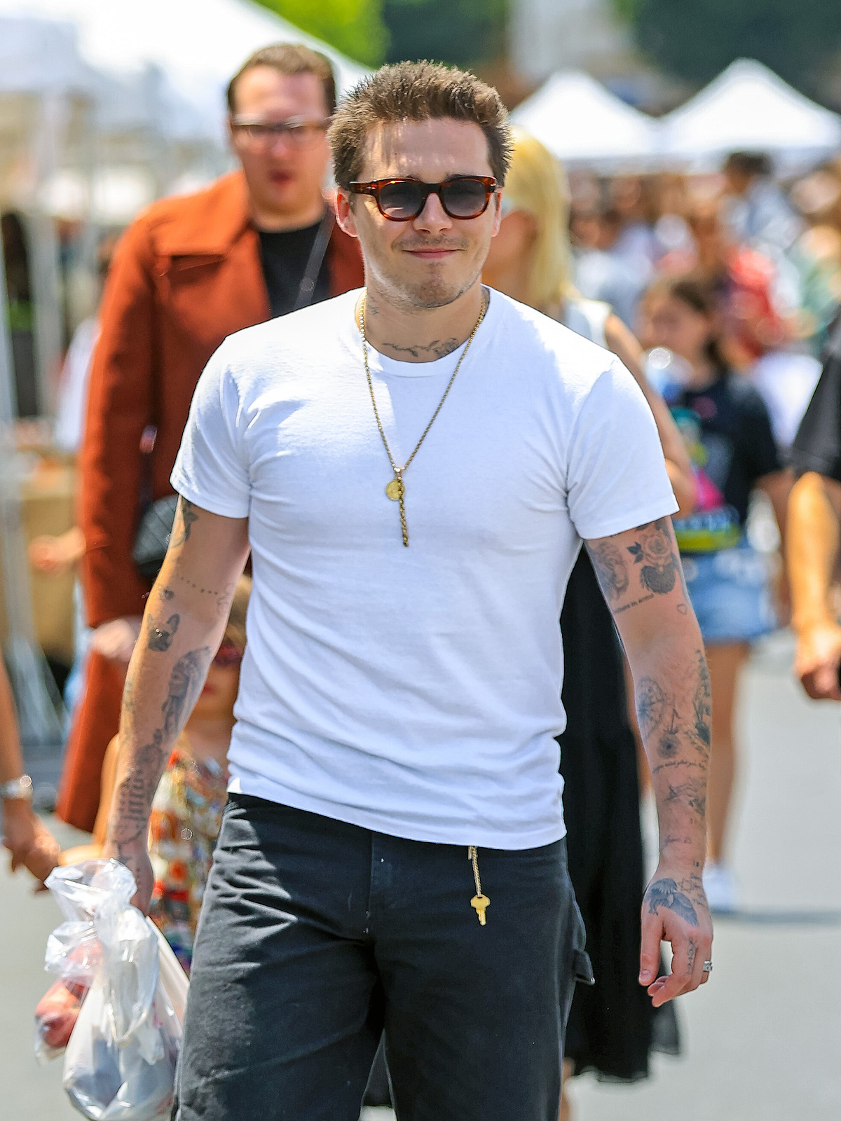 Brooklyn Beckham napszemüvegben és fehér pólóban sétál az utcán