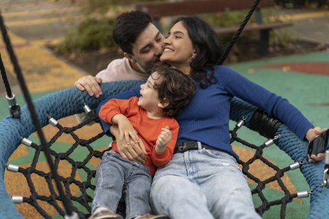 Kisgyerek és anyuka hintázik és egy férfi megcsókolja az anyukát