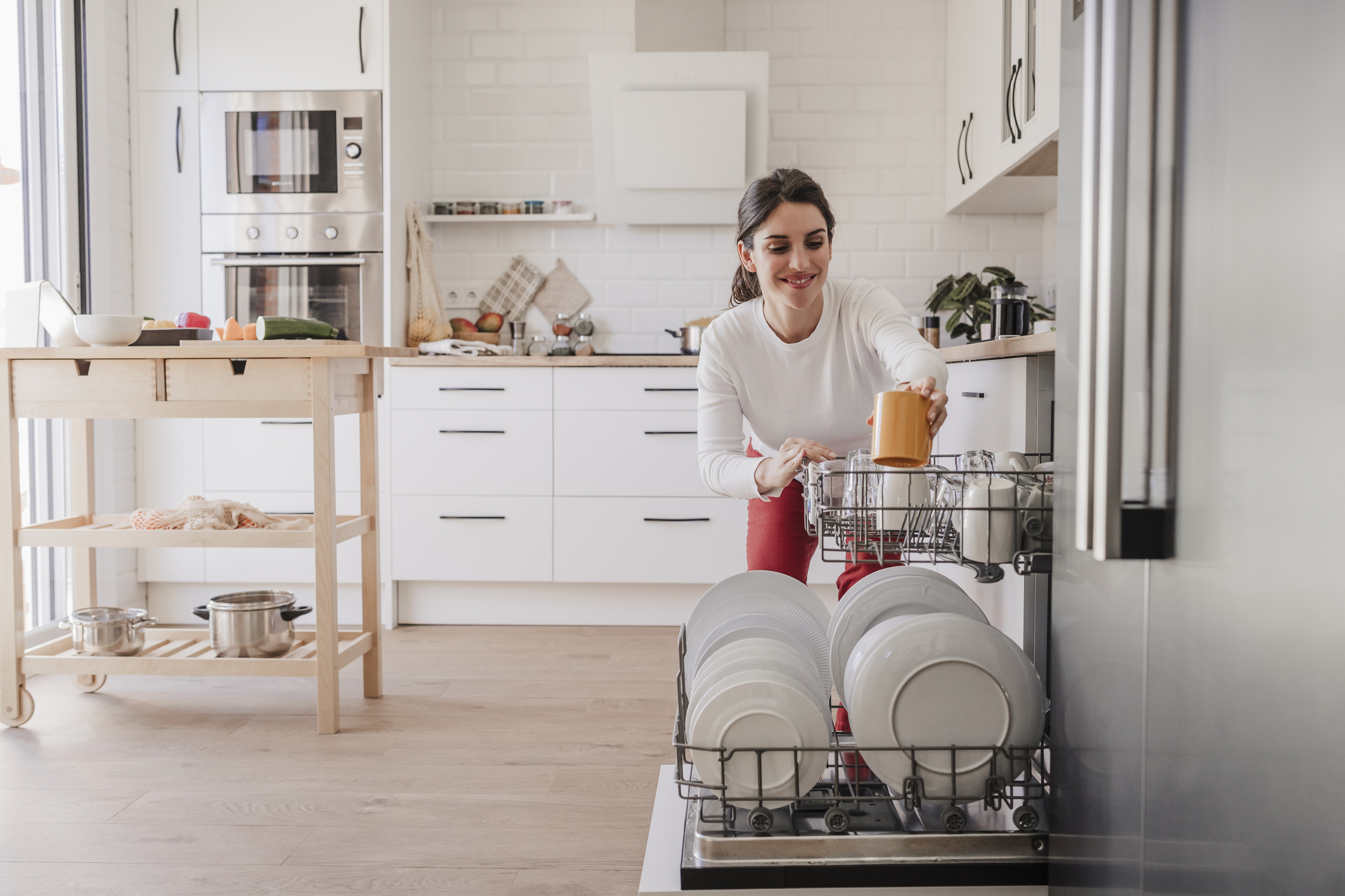 Nő, aki otthon a mosogatógépbe rakja az edényeket