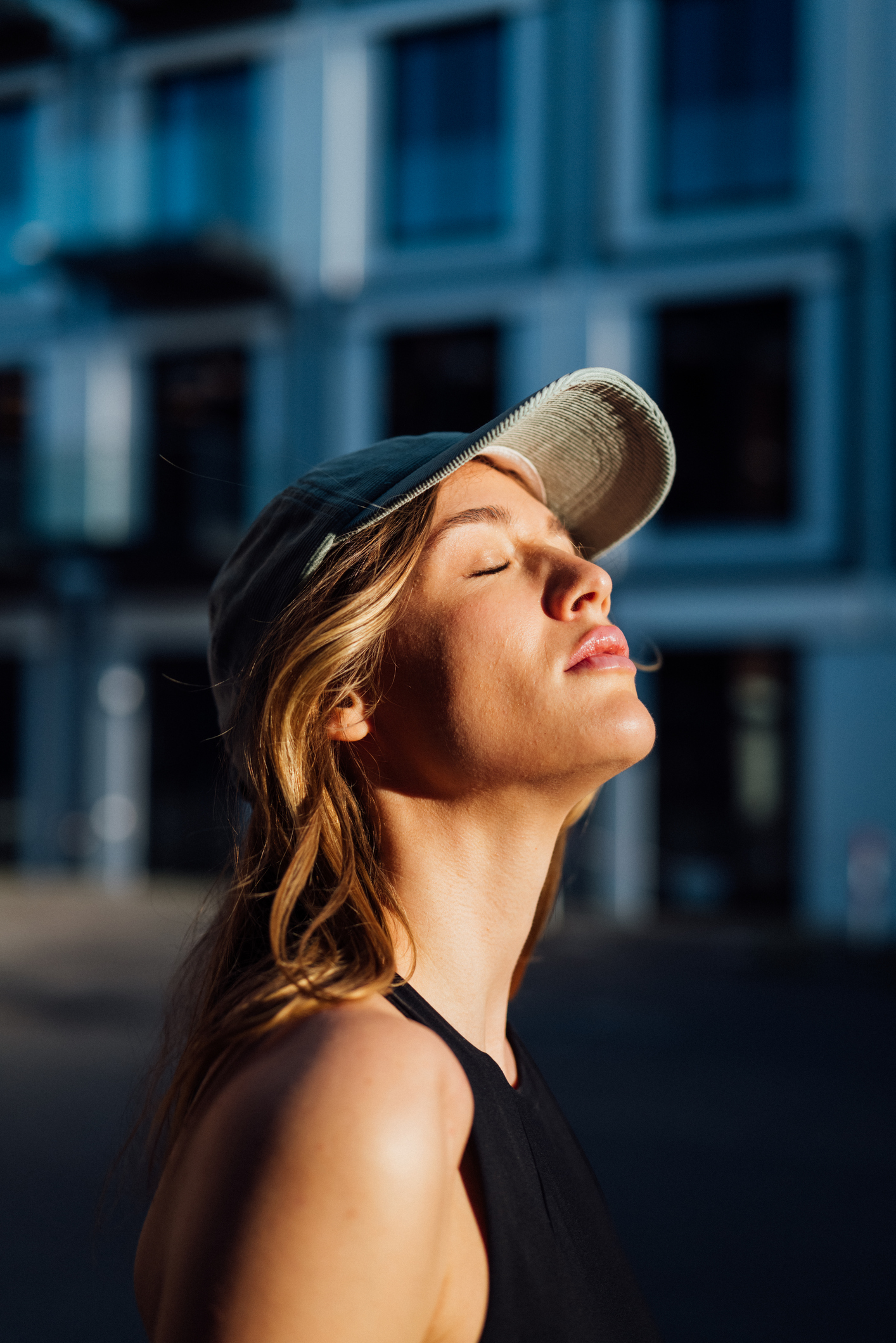 fiatal nő sapkában a nap felé tartja az arcát, edzés közben