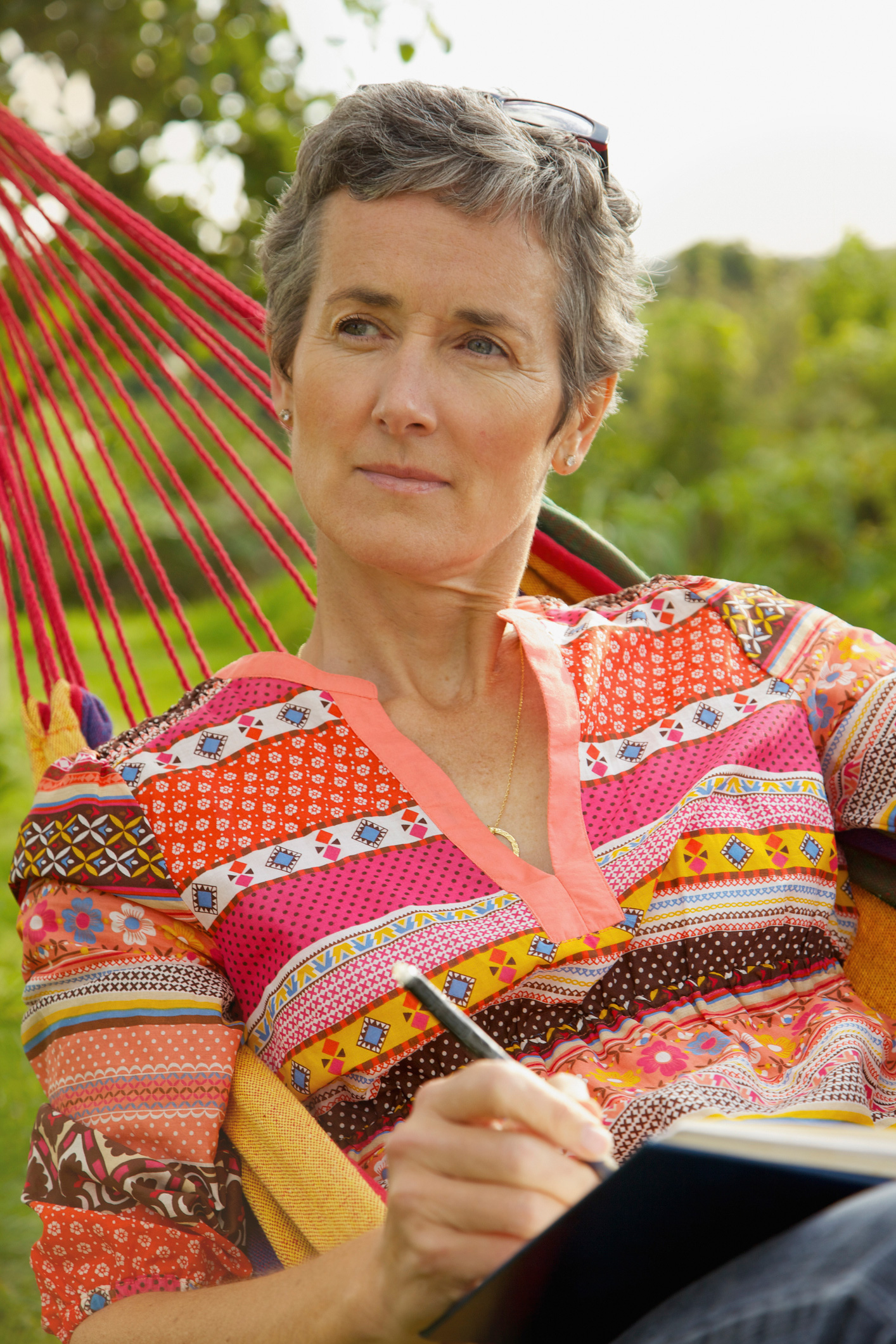 Egy idős nő elgondolkodva néz miközben egy függőágyban fekszik