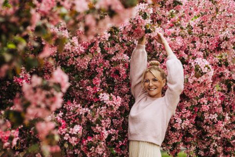 Mosolygó nő virágzó cseresznyefa előtt