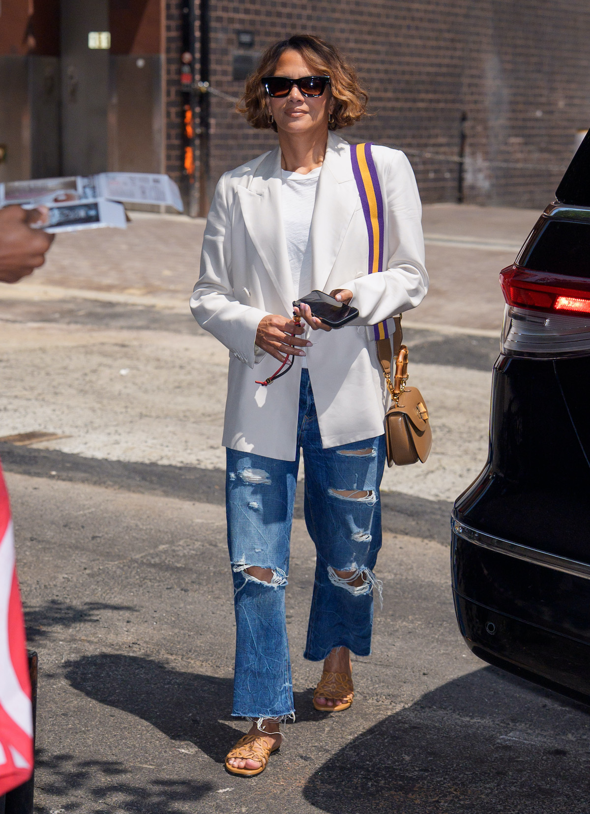 Halle Berry napszemüvegben, fehér blézerben és szakadt farmerben.