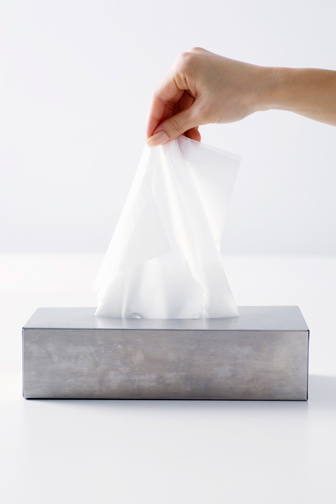 Egy nő kihúz egy darab zsebkendőt a tartóból