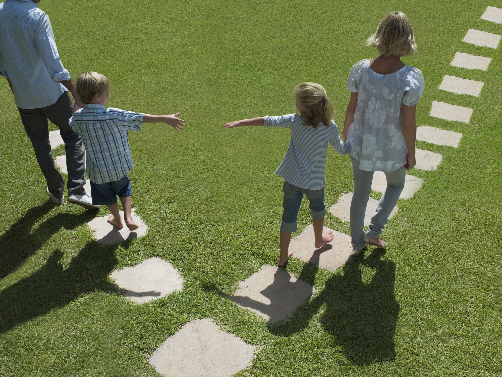 Anya, apa és két gyerek akik kinyújtják egymás felé a kezüket.