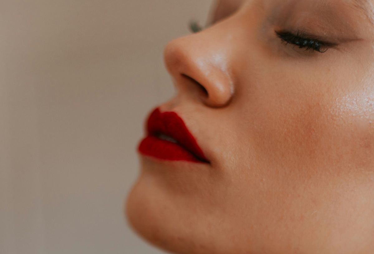 Szép, fiatal nő arca közelről, oldalnézetből, pirosra rúzsozott szájjal, kifestett szemmel