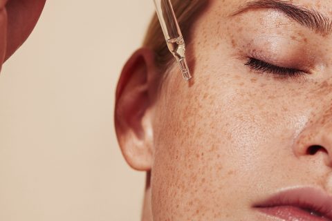 Női arc közelről, szérumot cseppent a bőrére