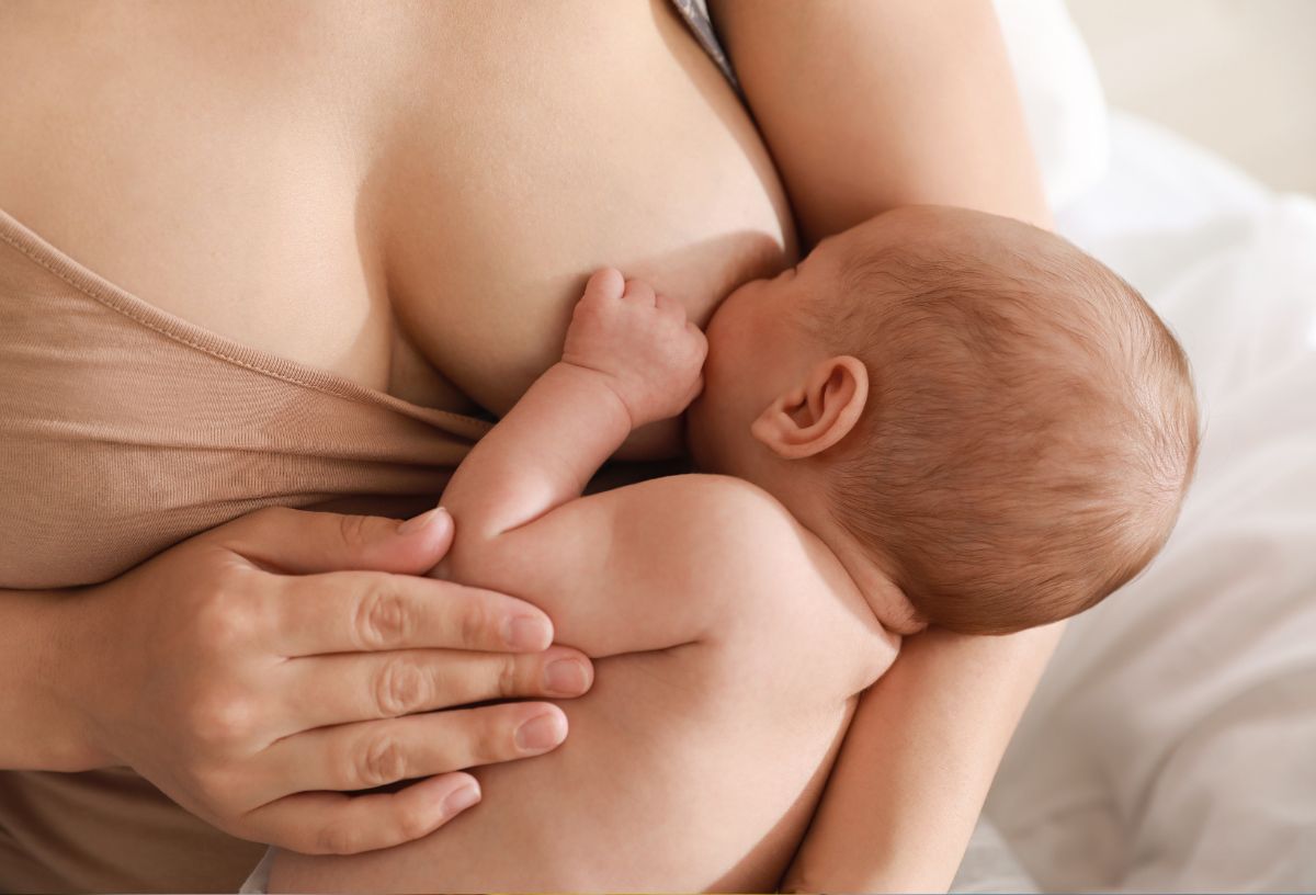 Nő szoptatja kisbabáját testszínű trikóban