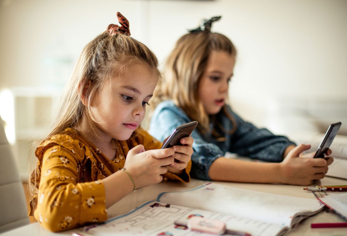 miert-nem-olvasnak-gyerekek | Marie Claire Két kislány asztalnál ülve okostelfont bámul