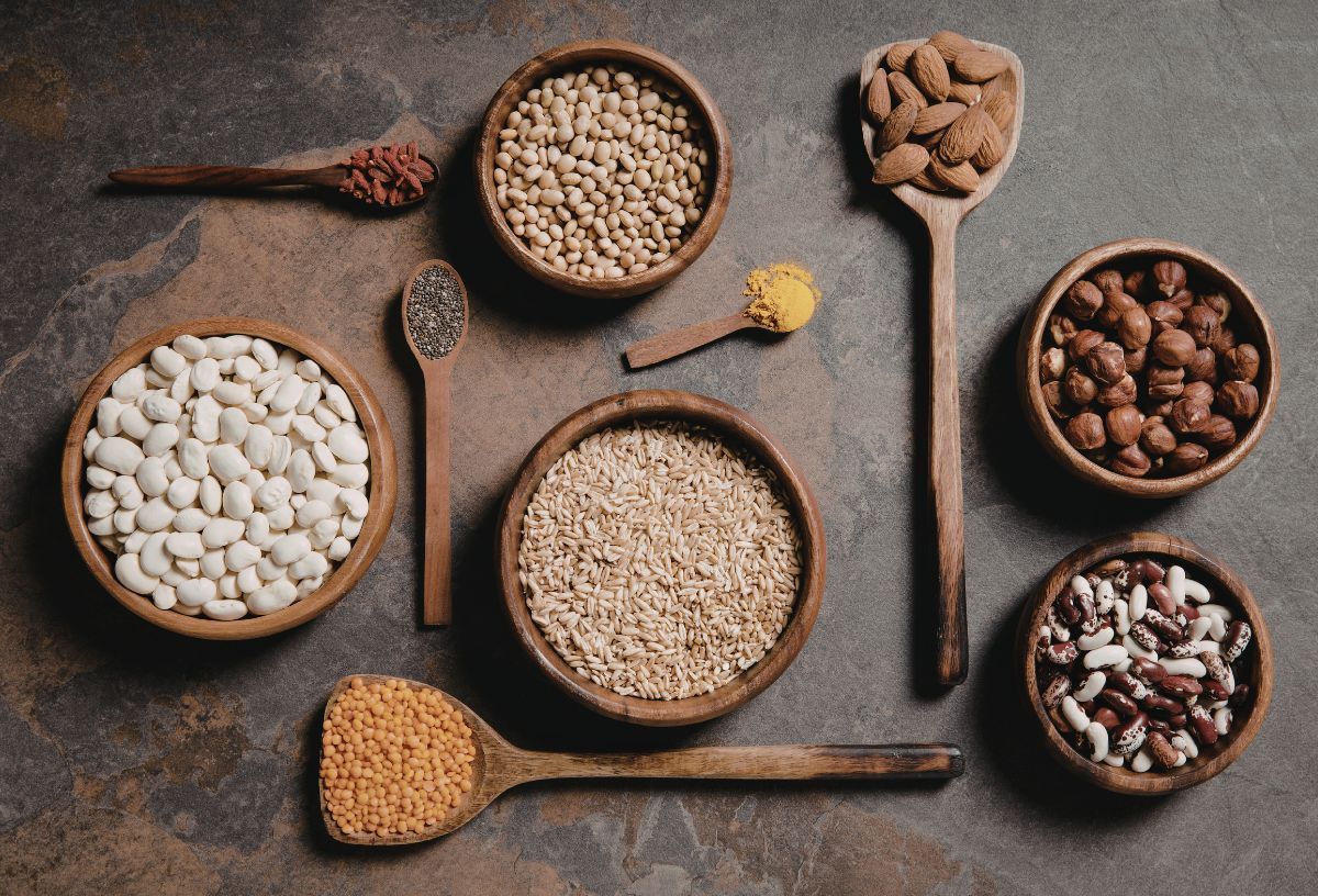 Egészséges gabonafélék barna fa tálkákban és kanalakban barna asztalon