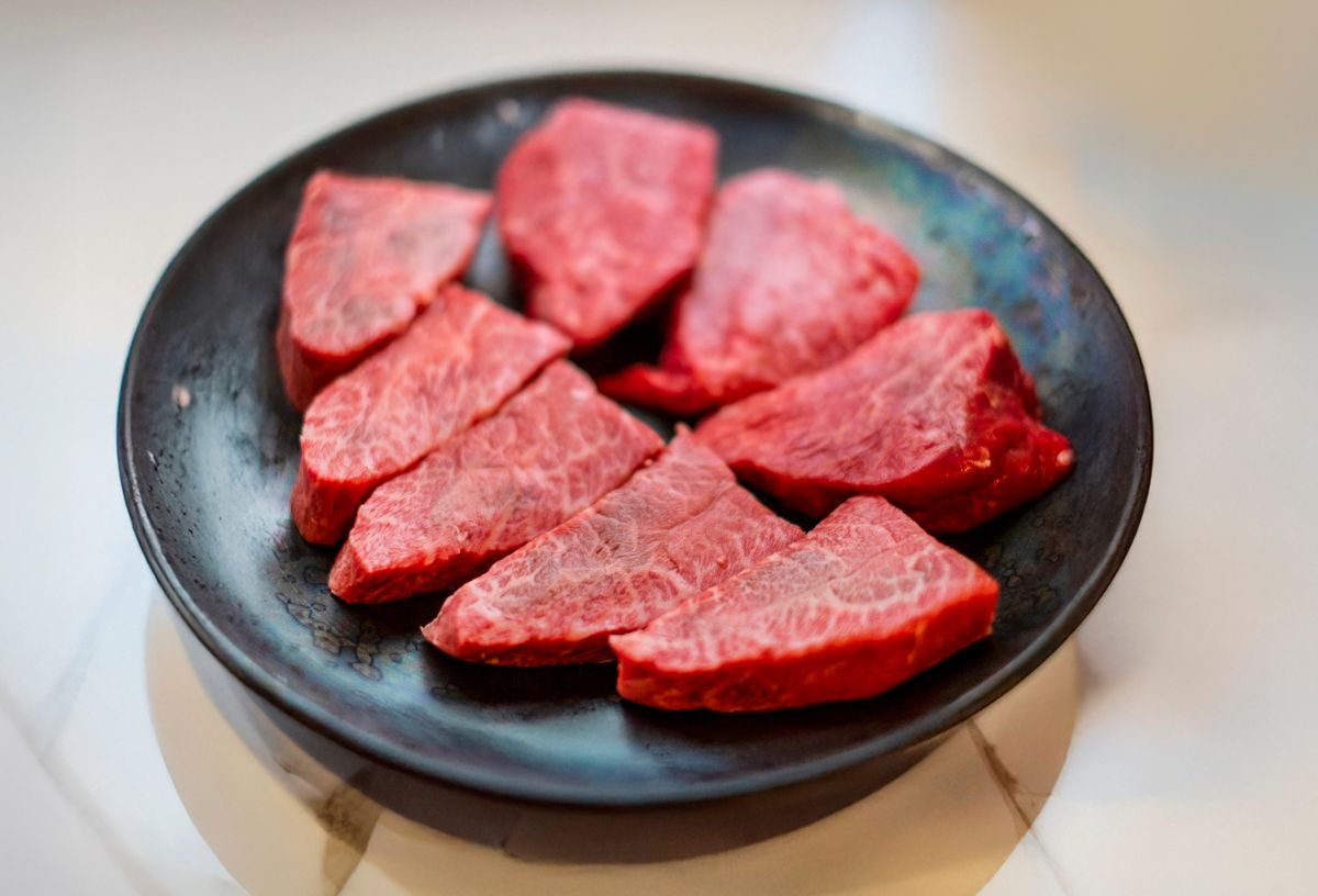 Vörös hússzeletek fekete tányéron
