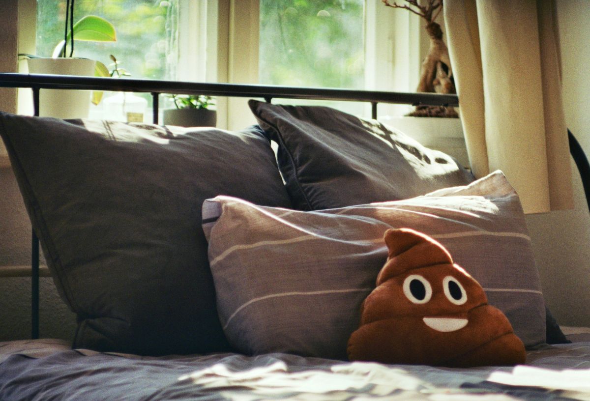 Ágy párnákkal és kaki emoji párnával hálószobában