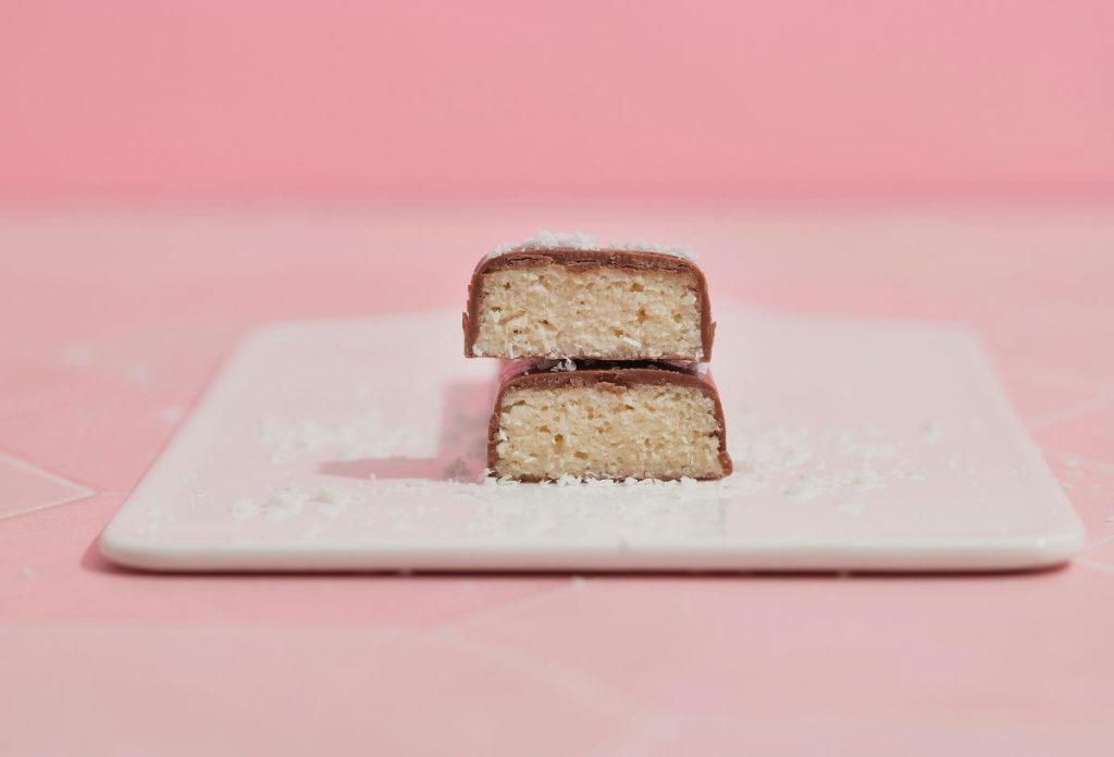 Félbevágott fehérjeszeletek egymáson fehér tányéron rózsaszín háttérrel