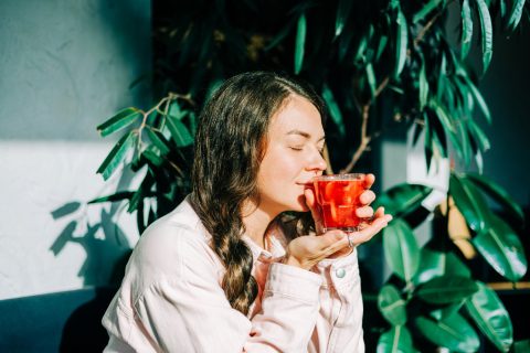 Egy nő a reggeli napsütésben gyümölcslevet iszik