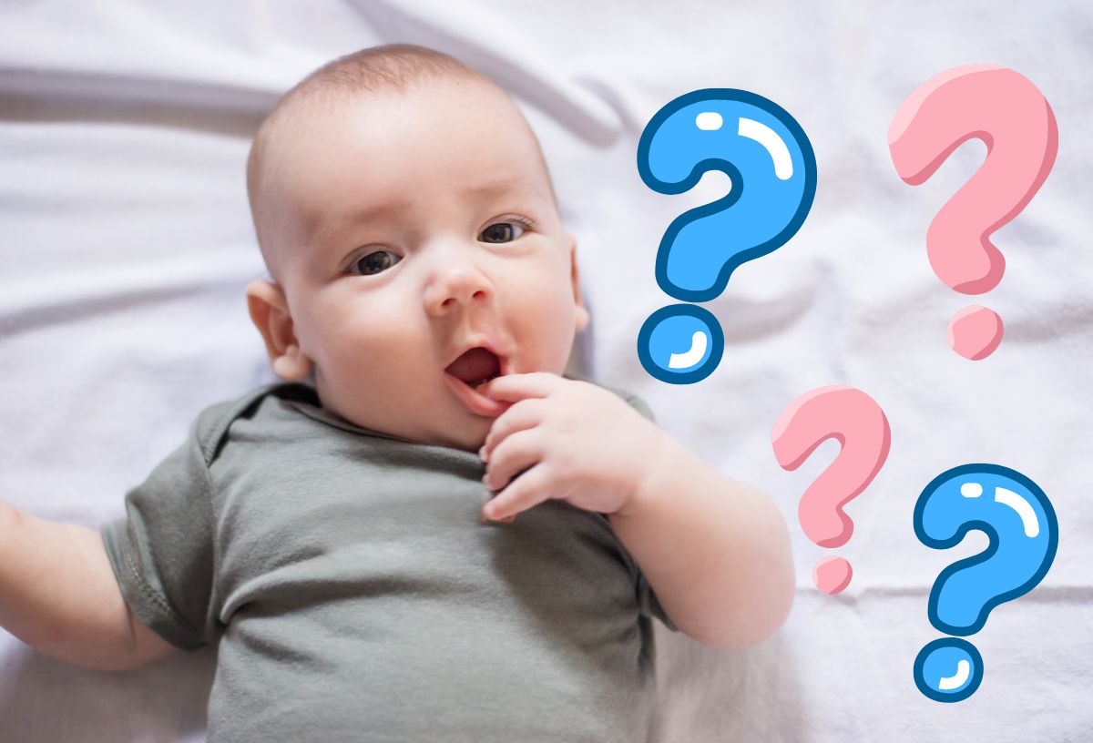 Kisbaba csodálkozó arckifejezéssel fekszik fehér lepedőn, mellette kék és rózsaszín kérdőjelek