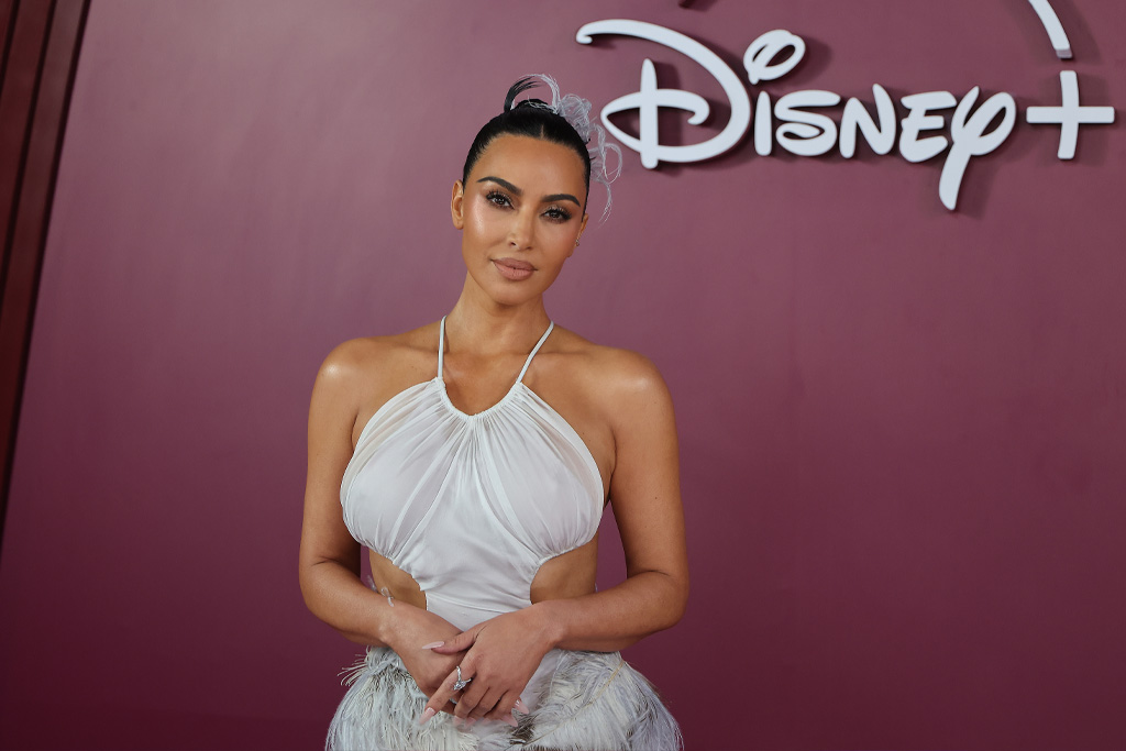 Kim Kardashian fehér ruhában mosolyog egyenesen a kamerába