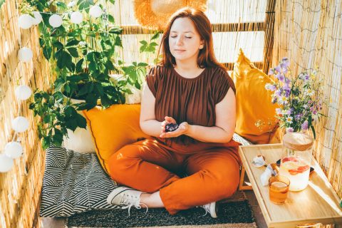 Egy nő ül az erkélyen törökülésben, kezében egy ásvány és meditál