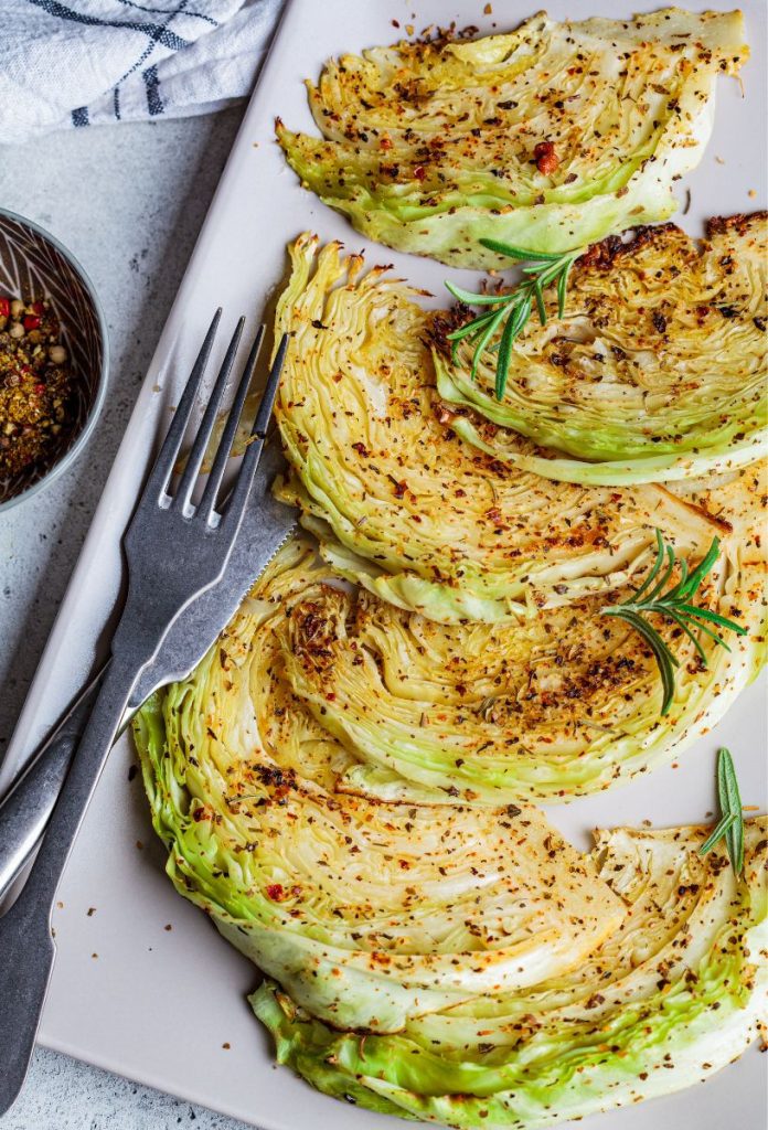 Olvadó káposzta fehér tányéron, mellette fém evőeszközök