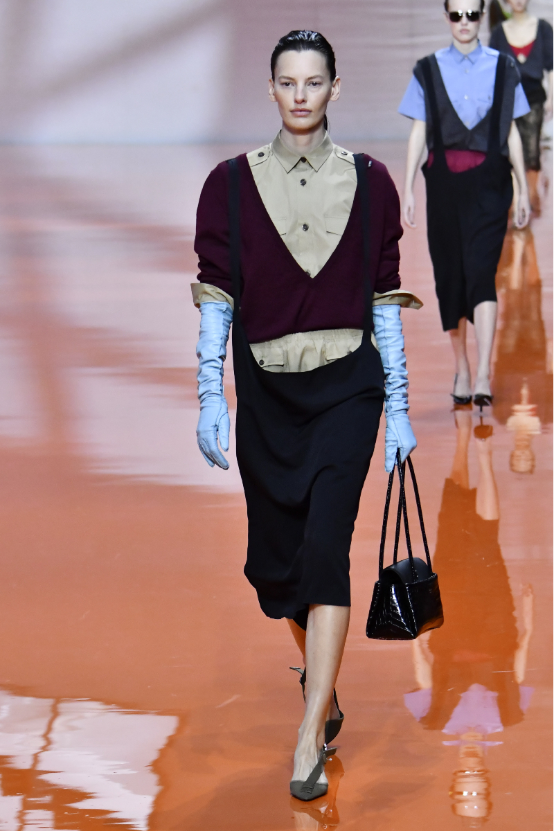 2026-tavasz-trend-library-chic-sikkes-konyvtaros | Marie Claire Barna hajú modell a Prada 2026. tavaszi–nyári bemutatóján hosszú kék bőrkesztyűben, bordó kardigánban, bézs ingben és sötét ceruzaszoknyában