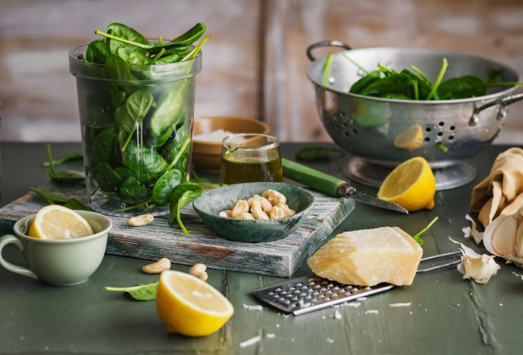 Spenótos étel hozzávalói: spenót mosótálban, magasfalú műanyag edényben, mellette kesudió kis tálkában, citrom félbevágva, parmezán és reszelő