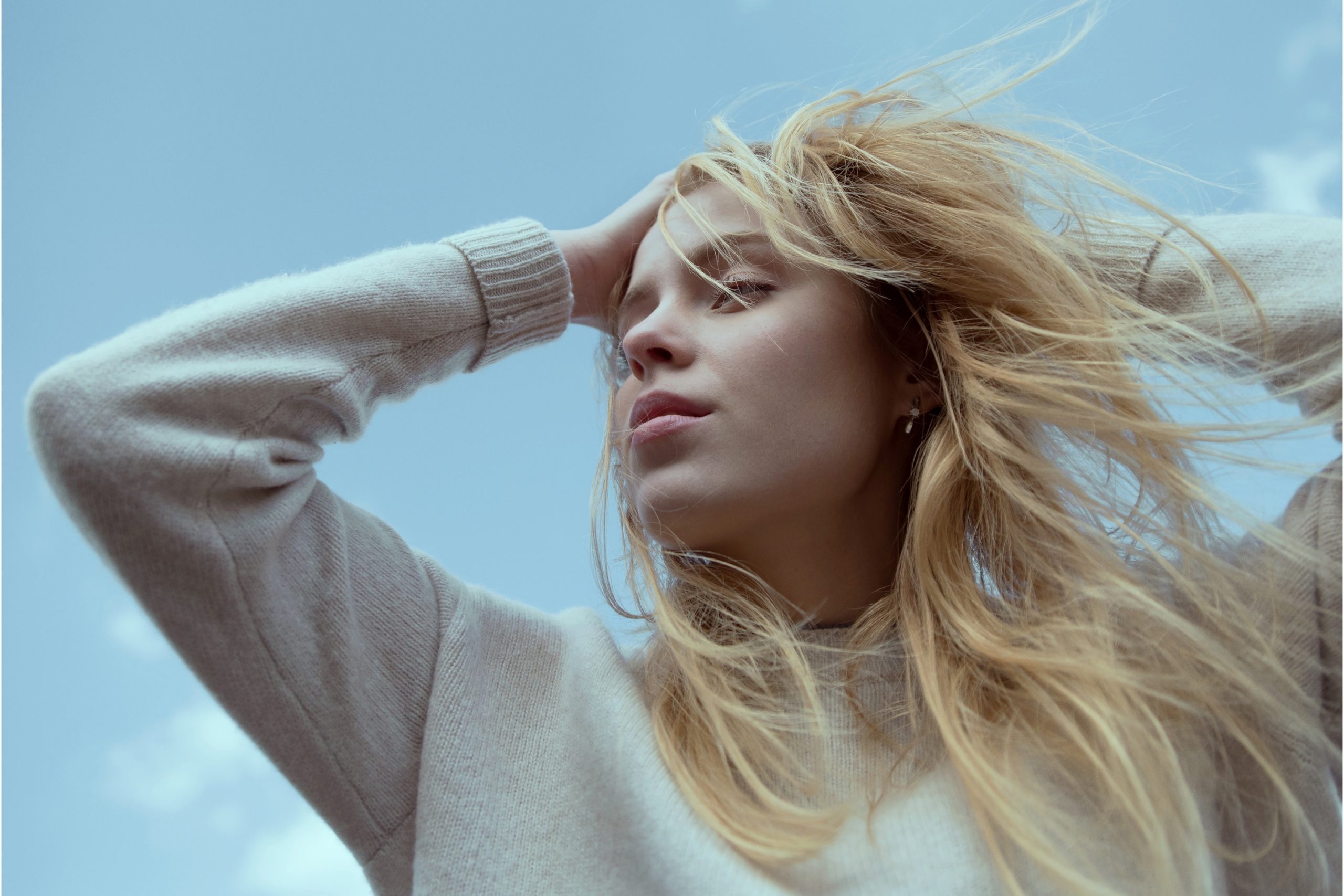 Fiatal nő szép hajjal, csukott szemmel, fújja a haját a szél