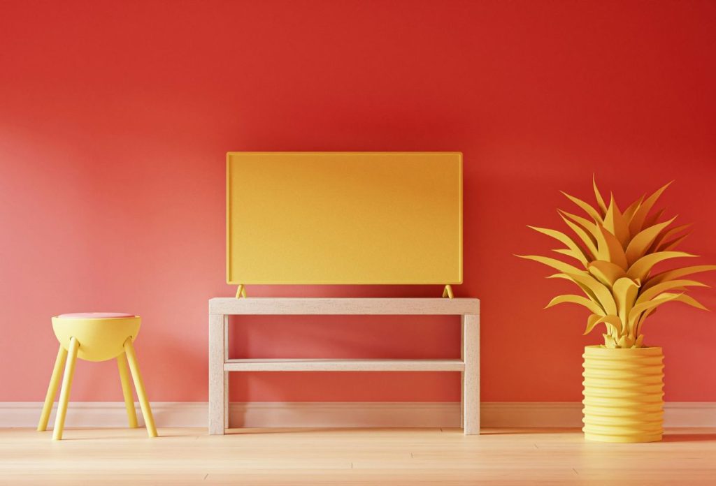 vajsarga-lakasdekoracio-2026 | Marie Claire Meleg narancspiros árnyalatú fal, sárga szék, váza műnövénnyel, komódelem