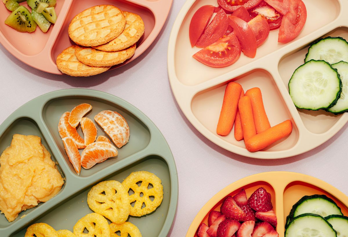 Osztott műanyag tányérok zöldség, gyümölcs és rágcsálnivaló falatkákkal