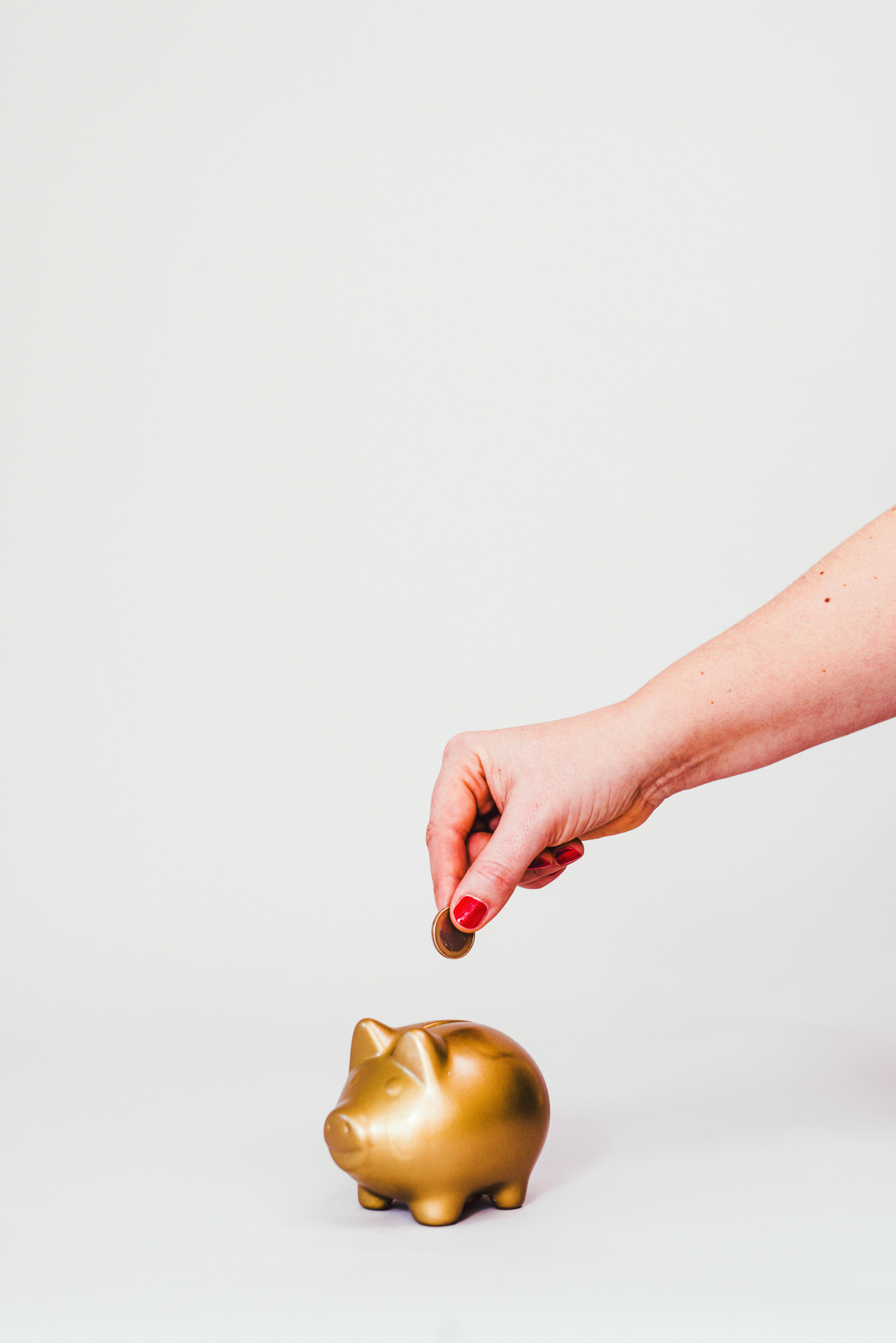 Egy nő pénzt dob az aranyszínű malacperselybe