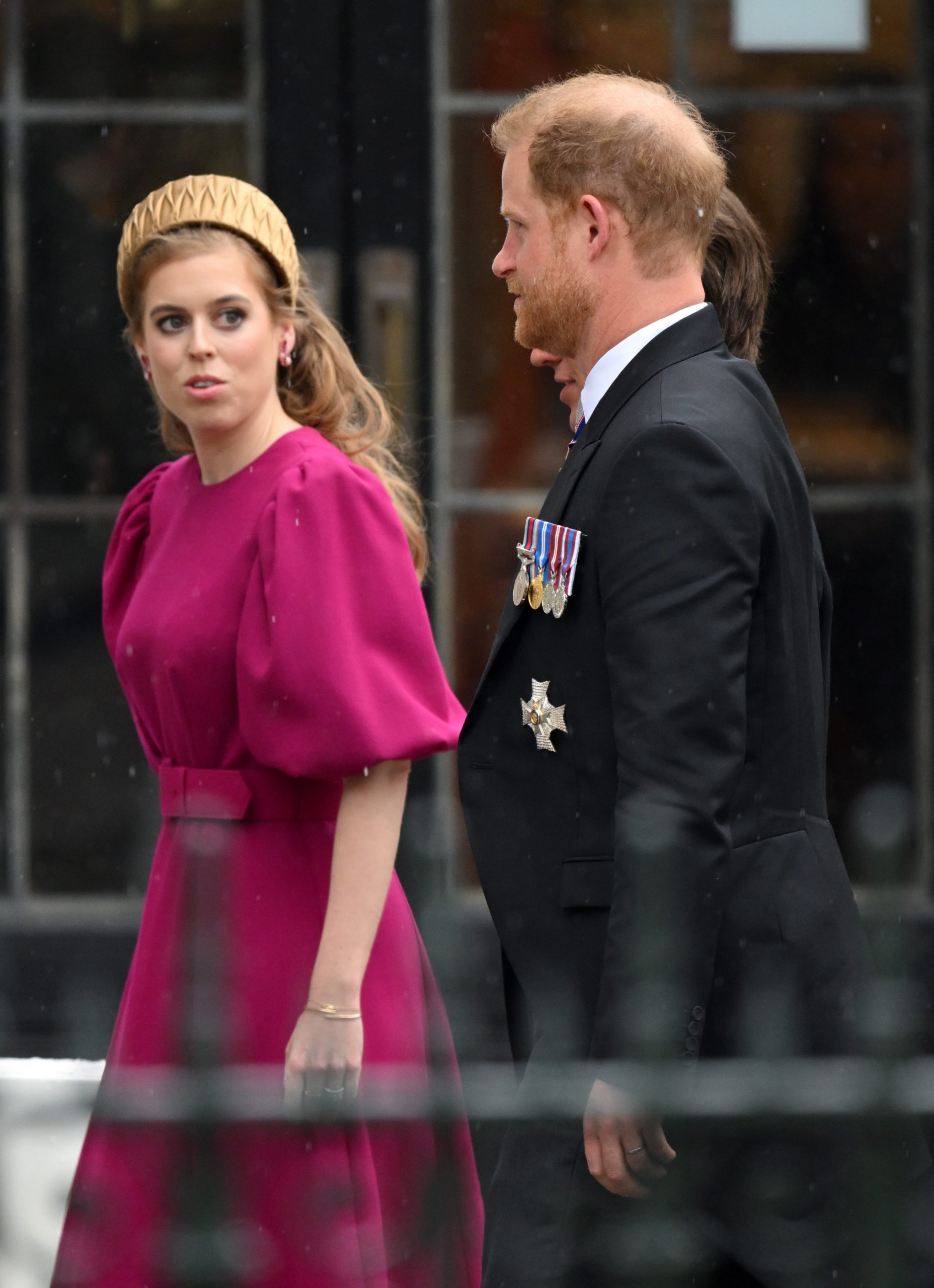 Beatrice ciklámen ruhában és mellette Harry egy hivatalos eseményen