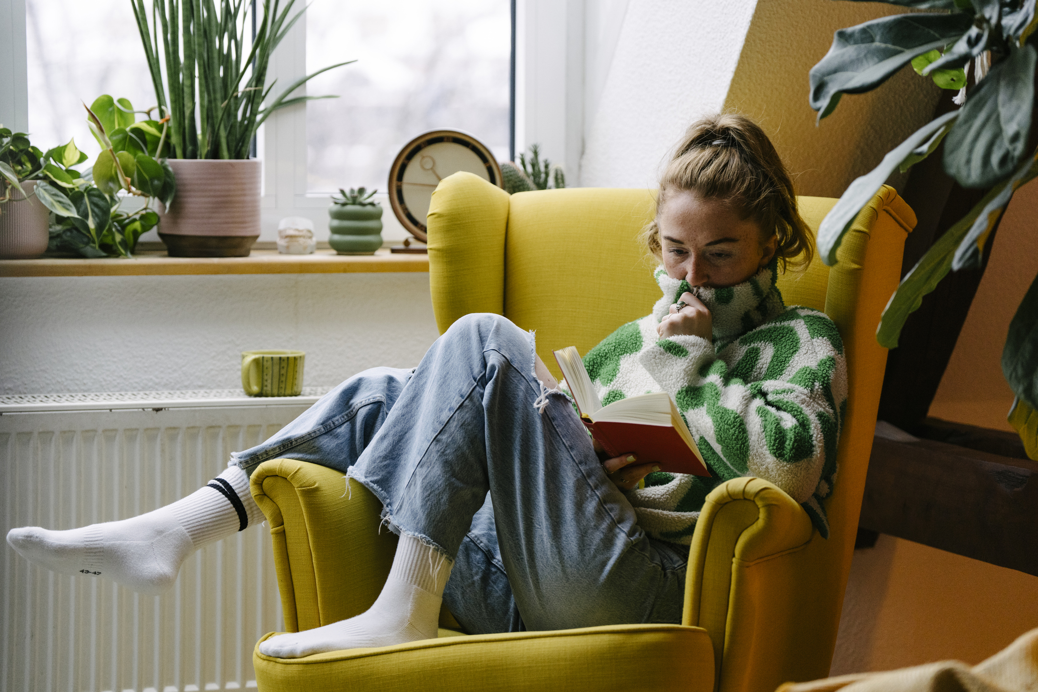 Nő otthon könyvet olvas.