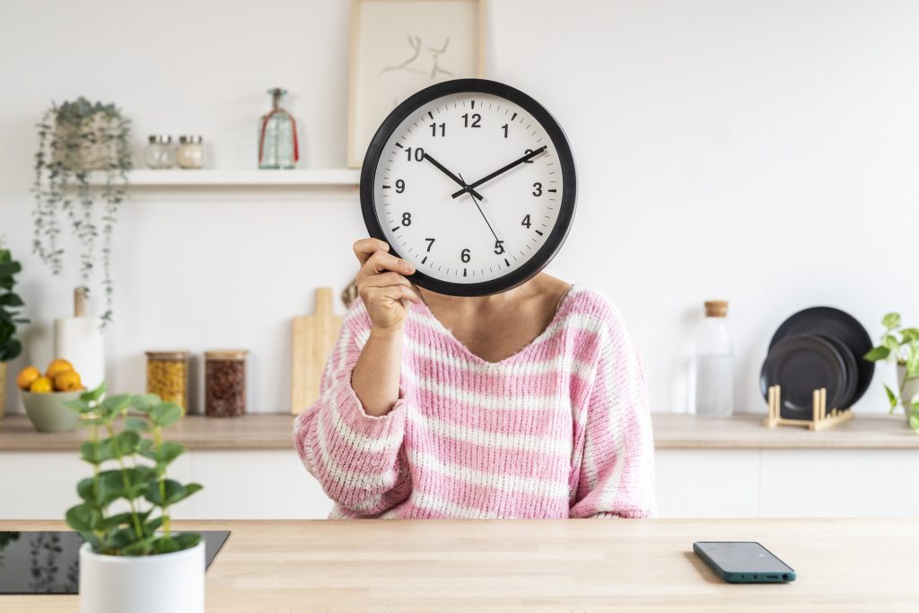 csíkos pulóveres nő órát tart az arca előtt