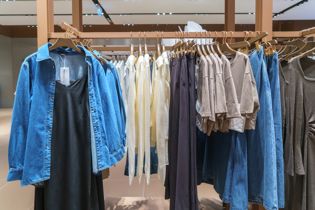 kék farmering és fekete ruha vállfán, mögötte más alapdarabok butikban