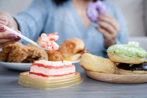 A nő túl sok gyorséttermi ételt fogyaszt, például hamburgert, sült csirkét, fánkot és édességet, ami túlzott evés és érzelmi stressz jeleit mutatja, valamint egészségtelen étkezési szokásokat.