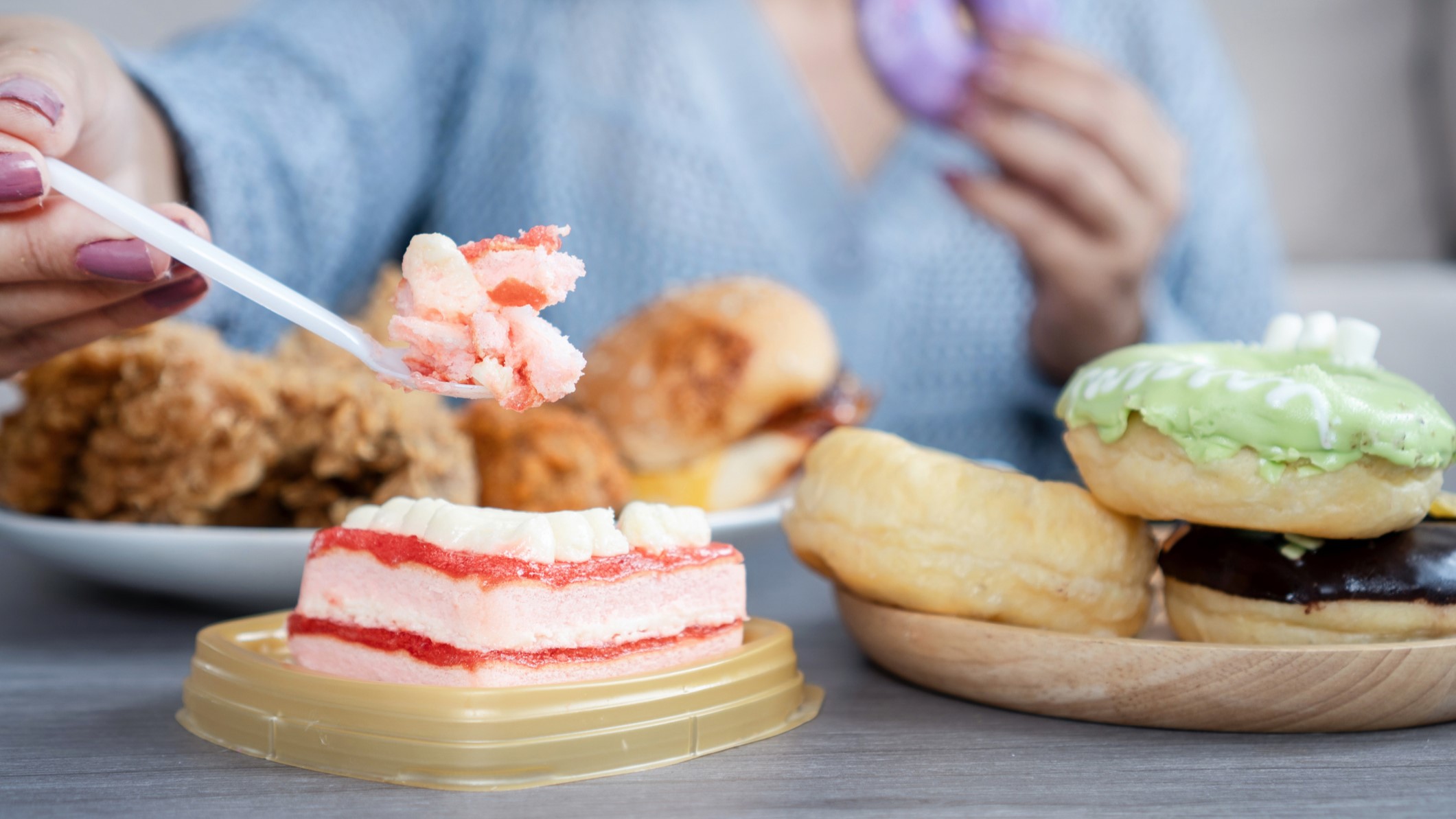 A nő túl sok gyorséttermi ételt fogyaszt, például hamburgert, sült csirkét, fánkot és édességet, ami túlzott evés és érzelmi stressz jeleit mutatja, valamint egészségtelen étkezési szokásokat.