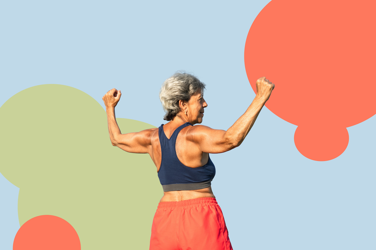 színes háttér előtt rövid hajú, ősz nő háttal felemelt karokkal, izmait mutatja, kék felsőben és narancssárga rövidnadrágban