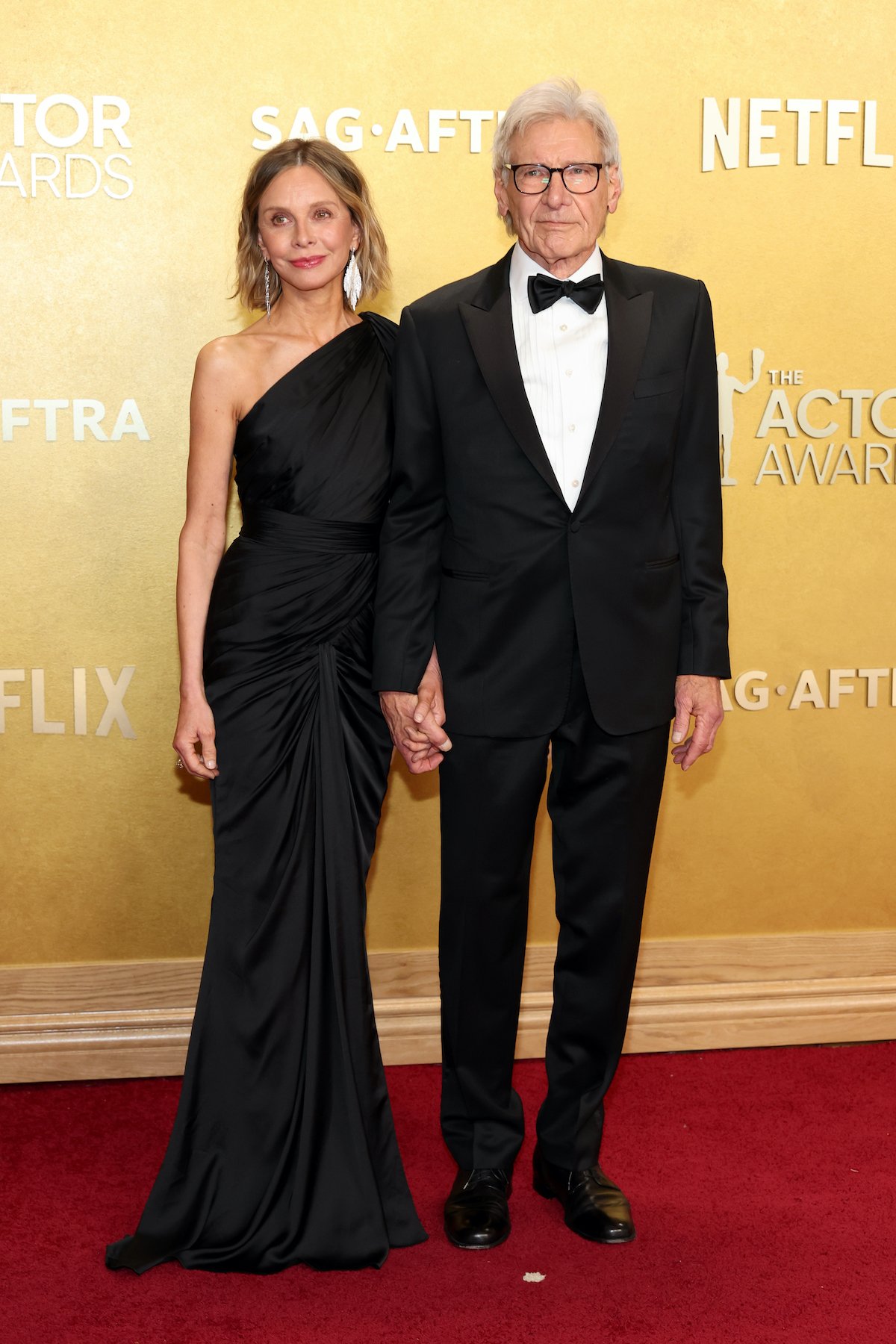 actor-awards-2026-harrison-ford-es-felesege-calista-flockhart | Marie Claire Calista Flockhart hosszú, fekete, asszimetrikus estélyiben és Harrison Ford fekete szmokingban az Actor Awards gálán.