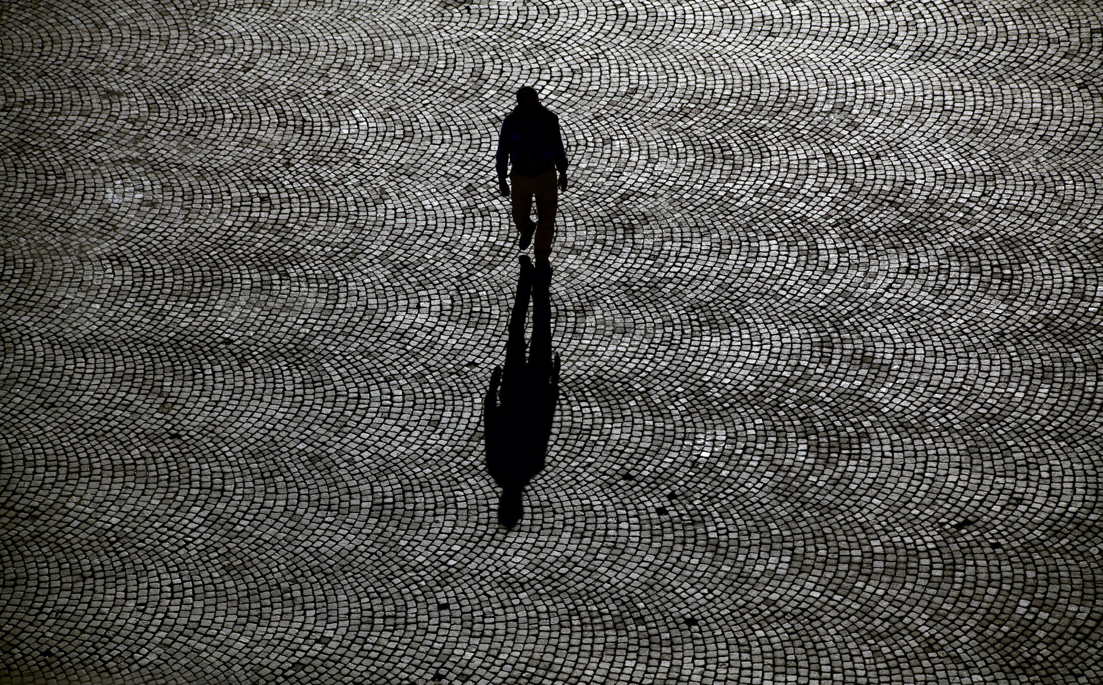 Egy férfi sétál egyedül a macskaköves utcán