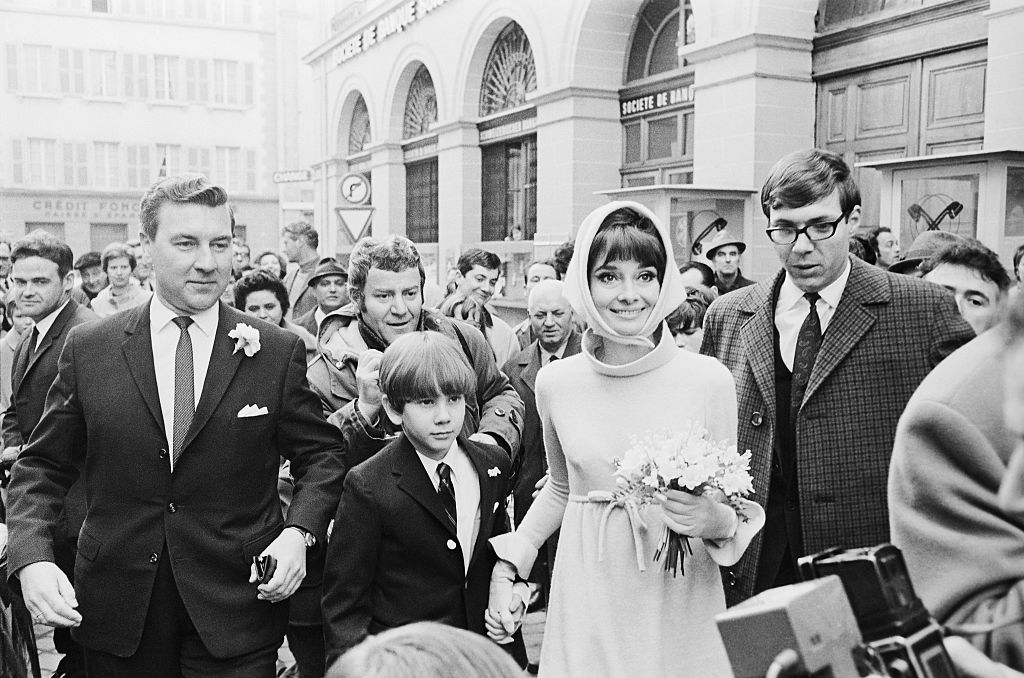 audrey-hepburn-csaladja-oroksege | Marie Claire Audrey Hepburn és férje, az olasz pszichiáter Dr. Andrea Dotti esküvőjük napján. Hepburn 39, Dotti 30 éves ekkor. A színésznő fehér ruhát, fejkendőt visel, kezében virágcsokor. Hatalmas tömeg veszi őket körül.