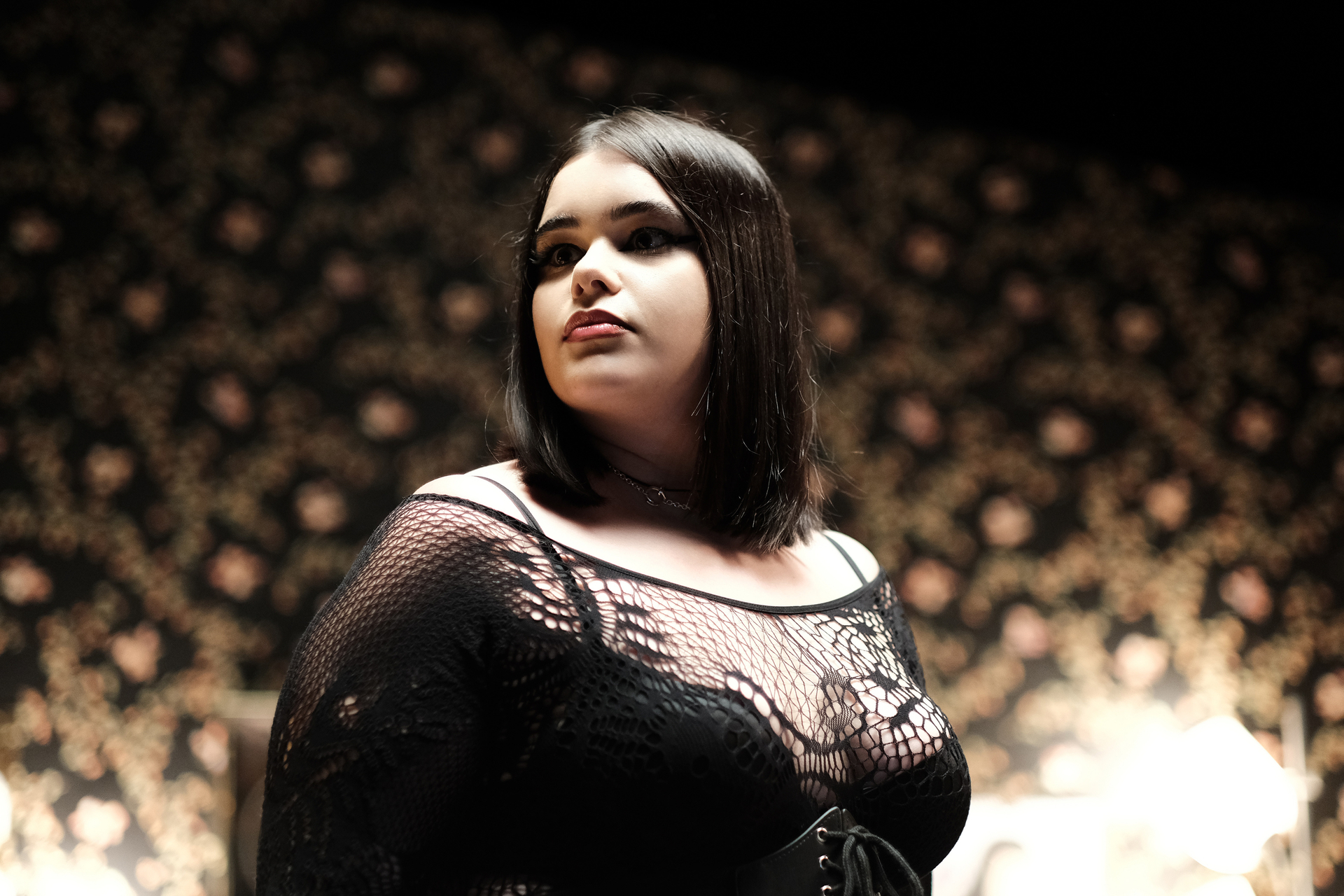 Barbie Ferreira fekete átlátszó hímzett felsőben oldalra néz.