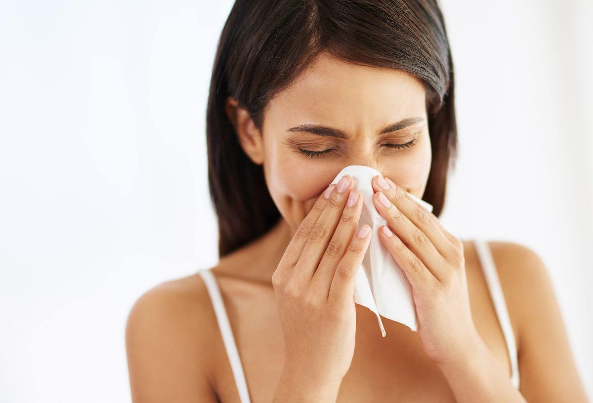 Barna hajú nő fehér zsebkendőbe fújja az orrát
