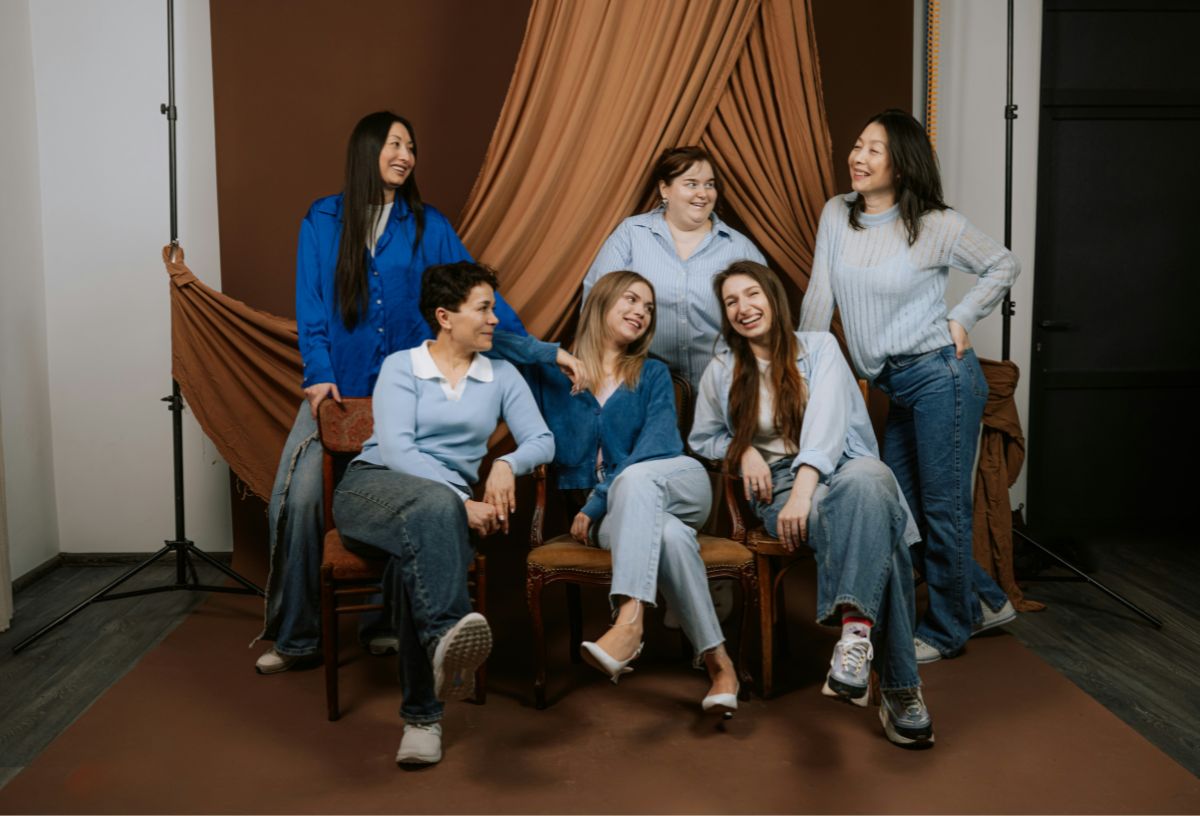 Hat nő céges fotózáson, három elöl kanapén ül keresztbetett lábbal, hárman mögöttük állnak