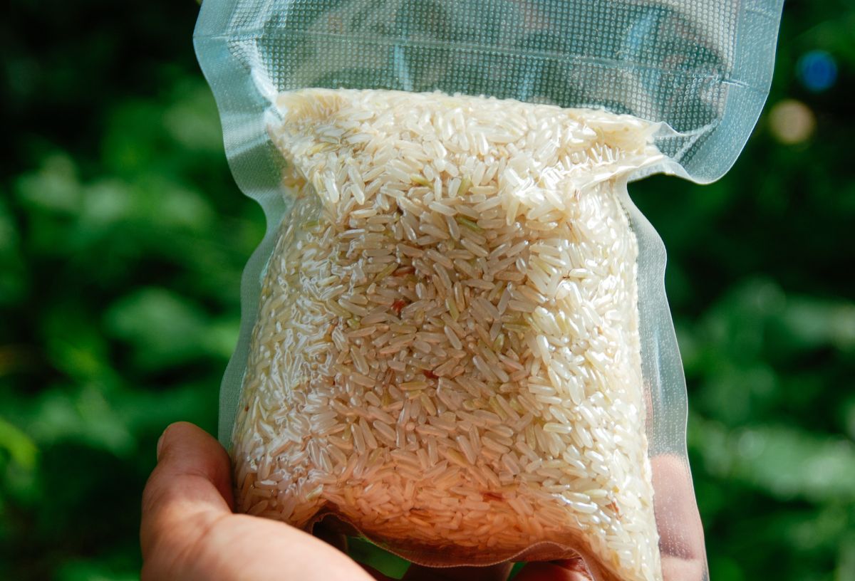 4 étel, amiben a legtöbb a mikroműanyag | Marie Claire Férfi kezében zacskós rizst tart zöld, növényi háttér előtt