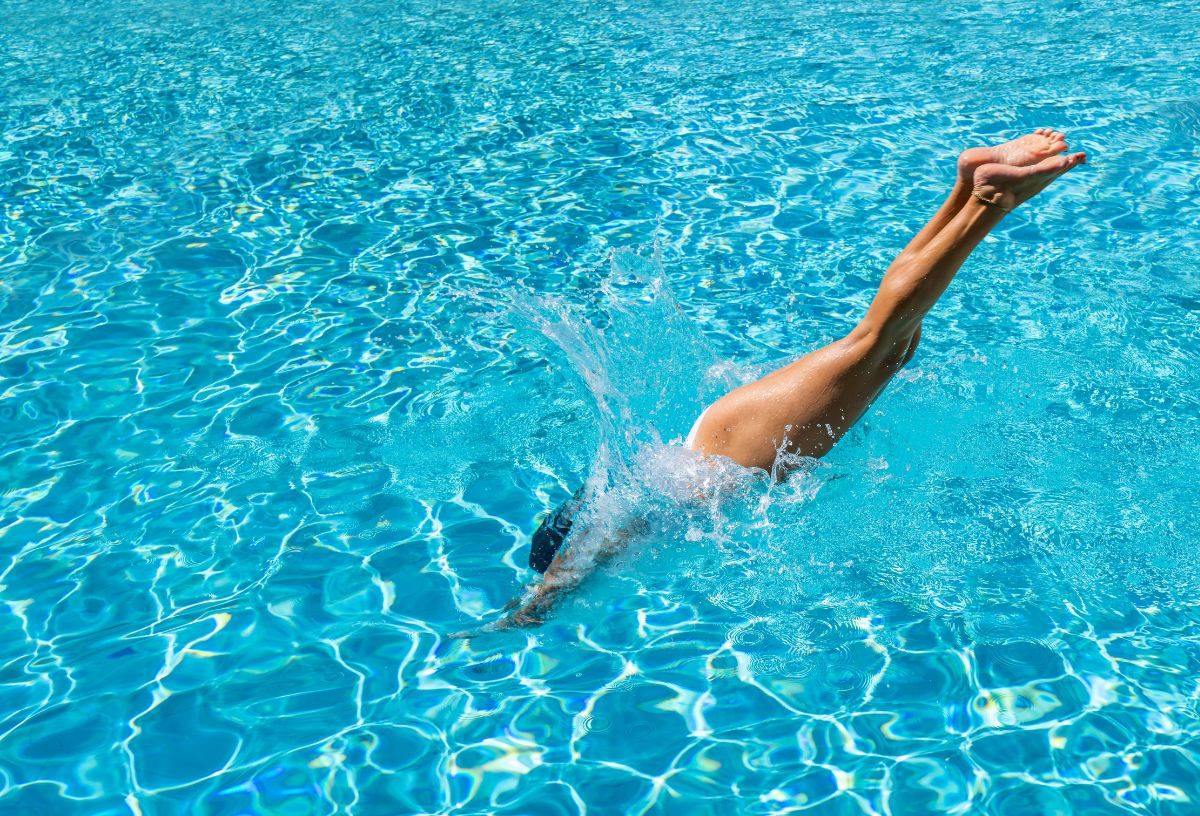 Nő fejest ugrik a medence kék vizébe