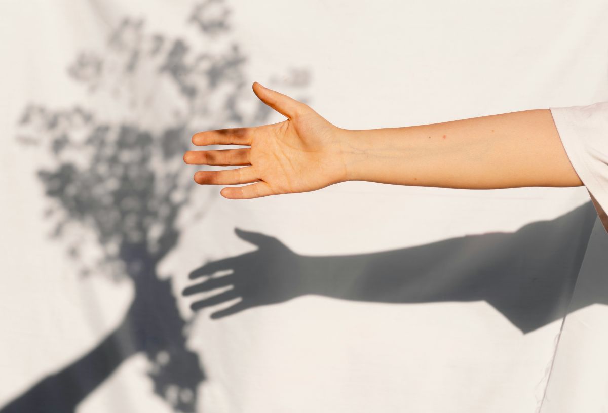 Kinyújtott kéz és árnyéka fehér falon