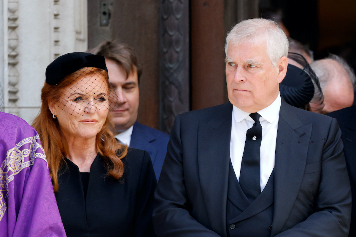 Sarah Ferguson fekete kosztümben és kalapban és mellette András herceg