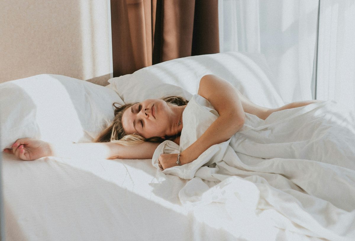 Nő fehér ágyneműben alszik a hálószobában