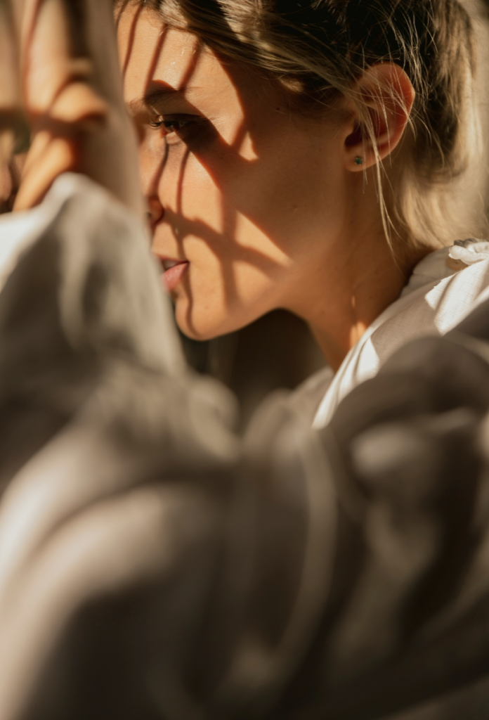 Nő közeli képen ablakon néz ki, árnyékok vetülnek az arcára