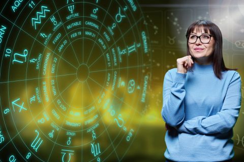Egy szemüveges nő komoly arccal nézi a zodiákus kört